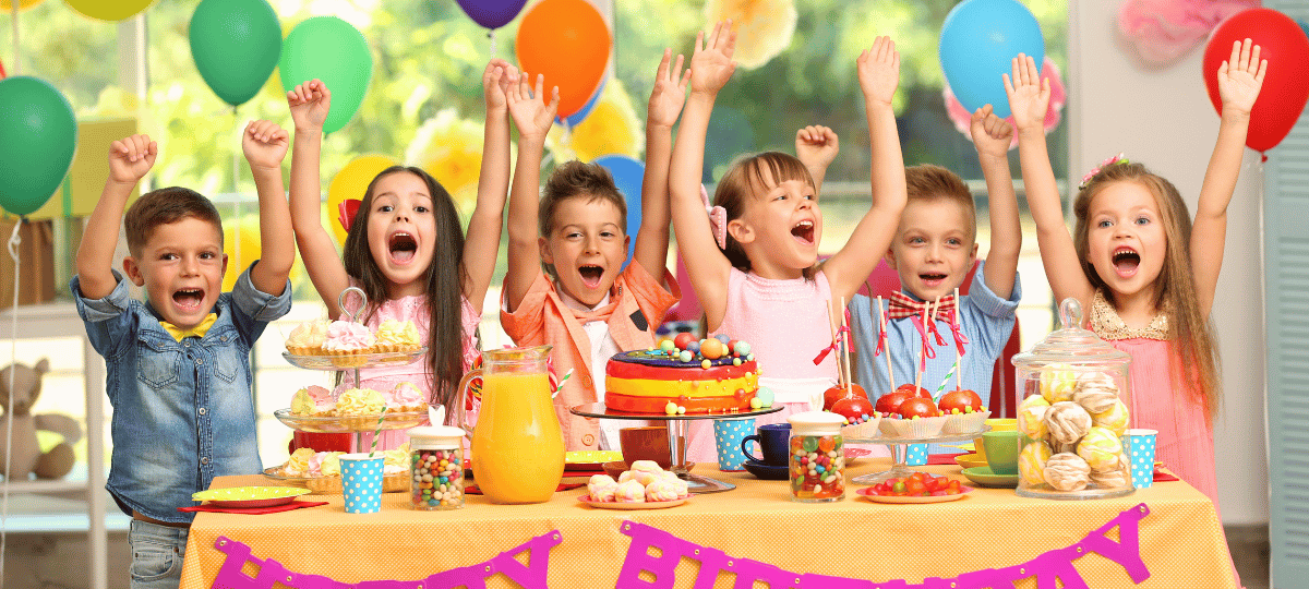 Fröhliches Stimmungsbild für einen Kindergeburtstag mit bunten Ballons, Girlanden, Geburtstagstorte, Konfetti und festlich dekoriertem Partytisch.