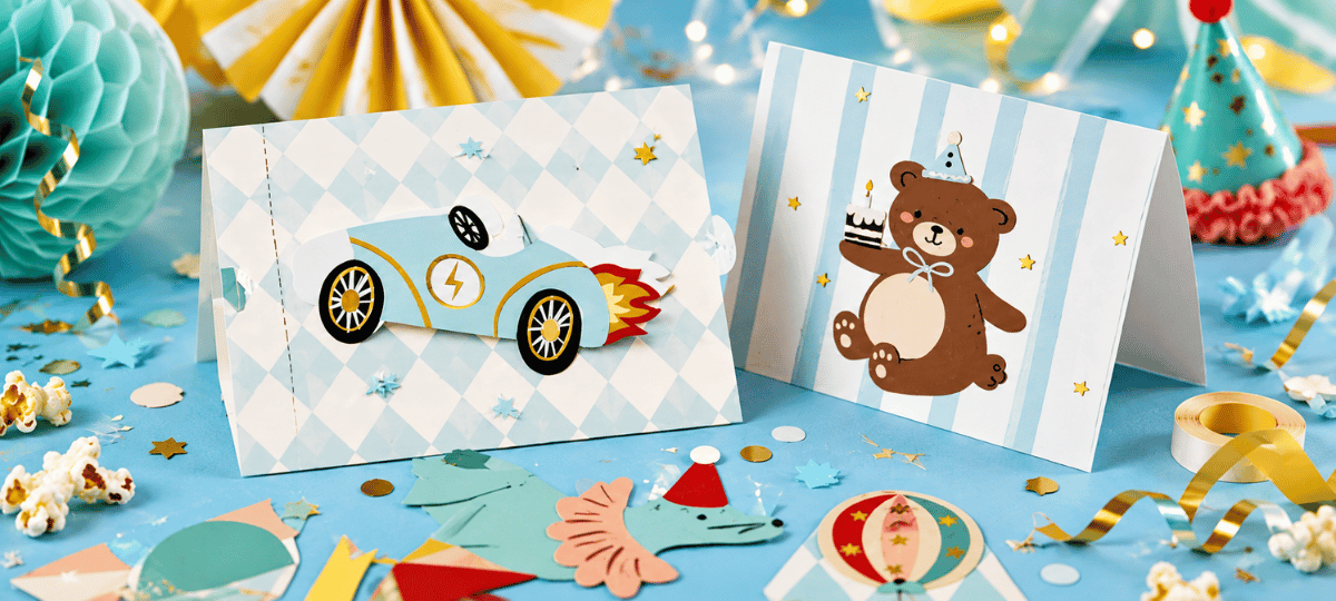 Bunte Geburtstagseinladungen für Kinder mit Auto- und Teddybär-Motiv auf festlich dekoriertem Geburtstagstisch.